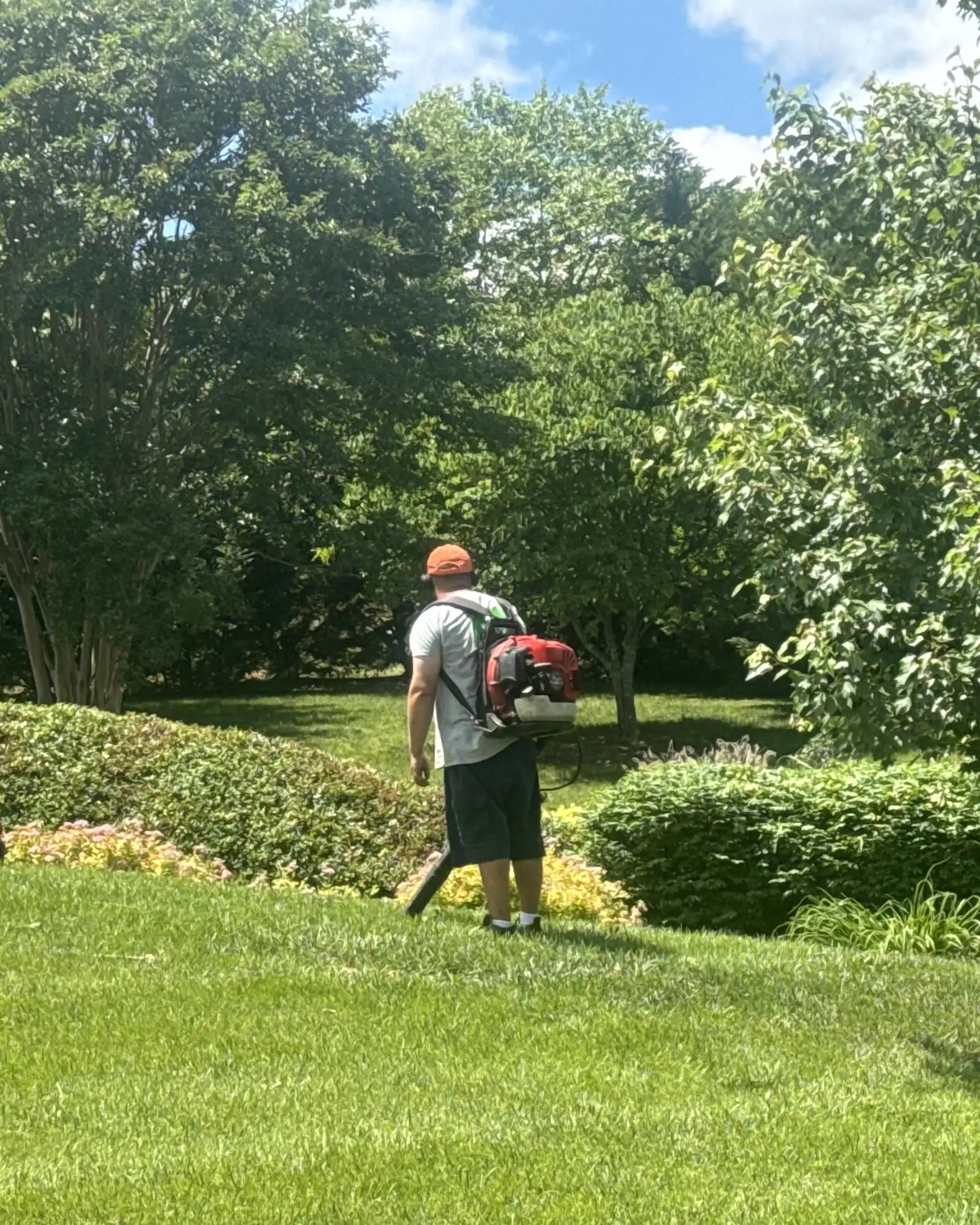 Crew member using a backpack blower on a landscaped property.