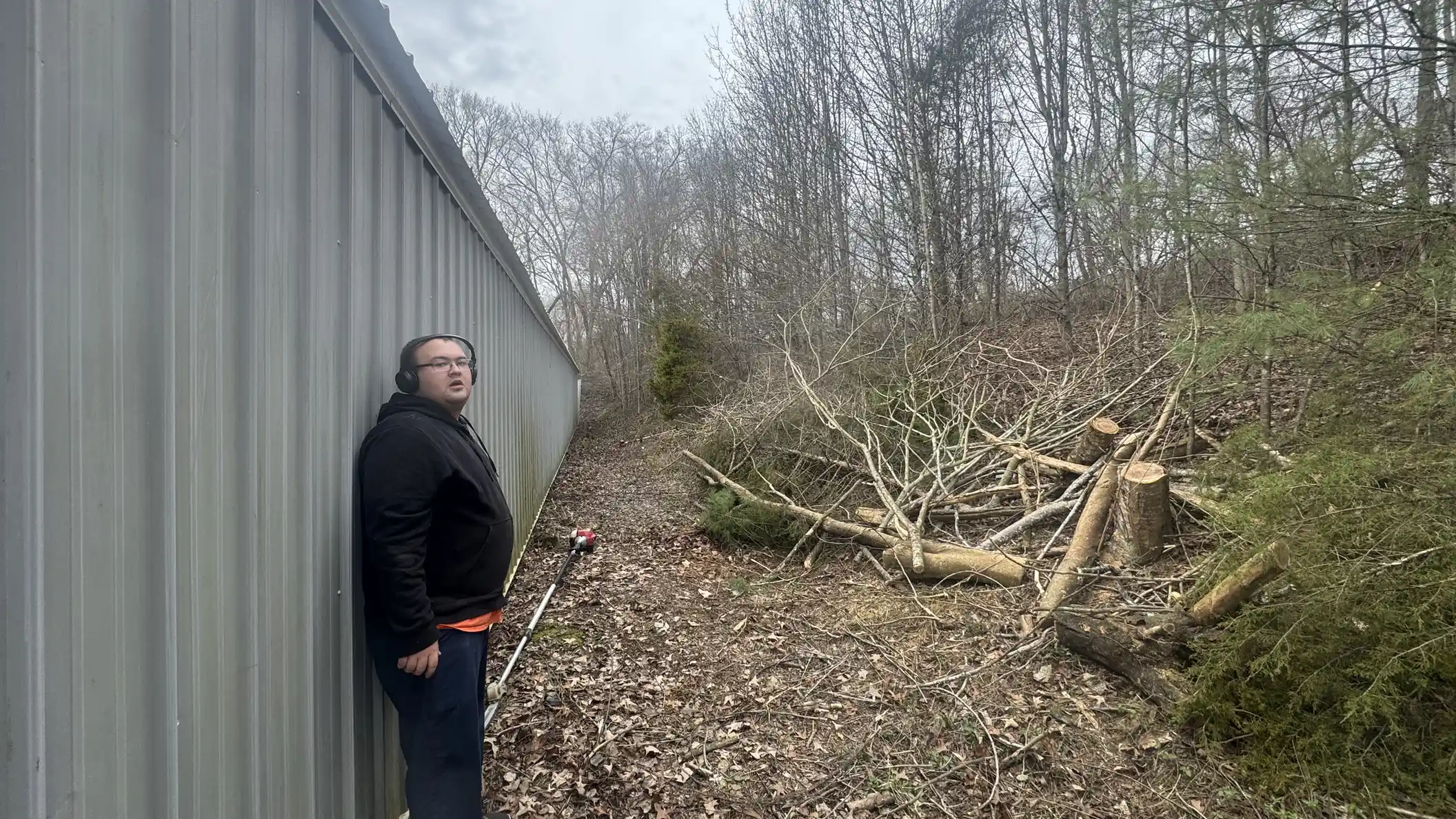 Worker beside cut branches ready for debris removal.