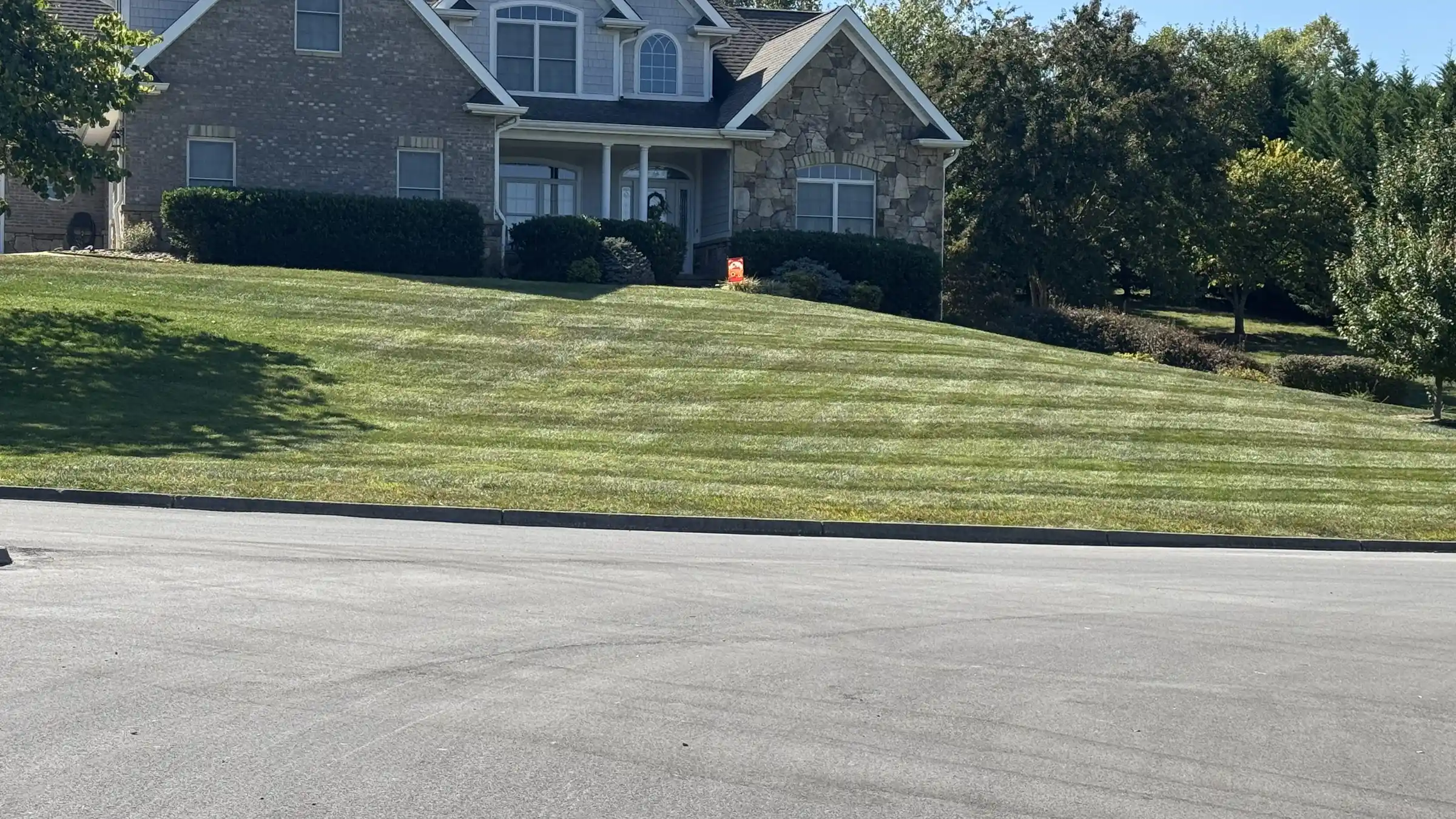 Fresh mowing stripes across a large front lawn.